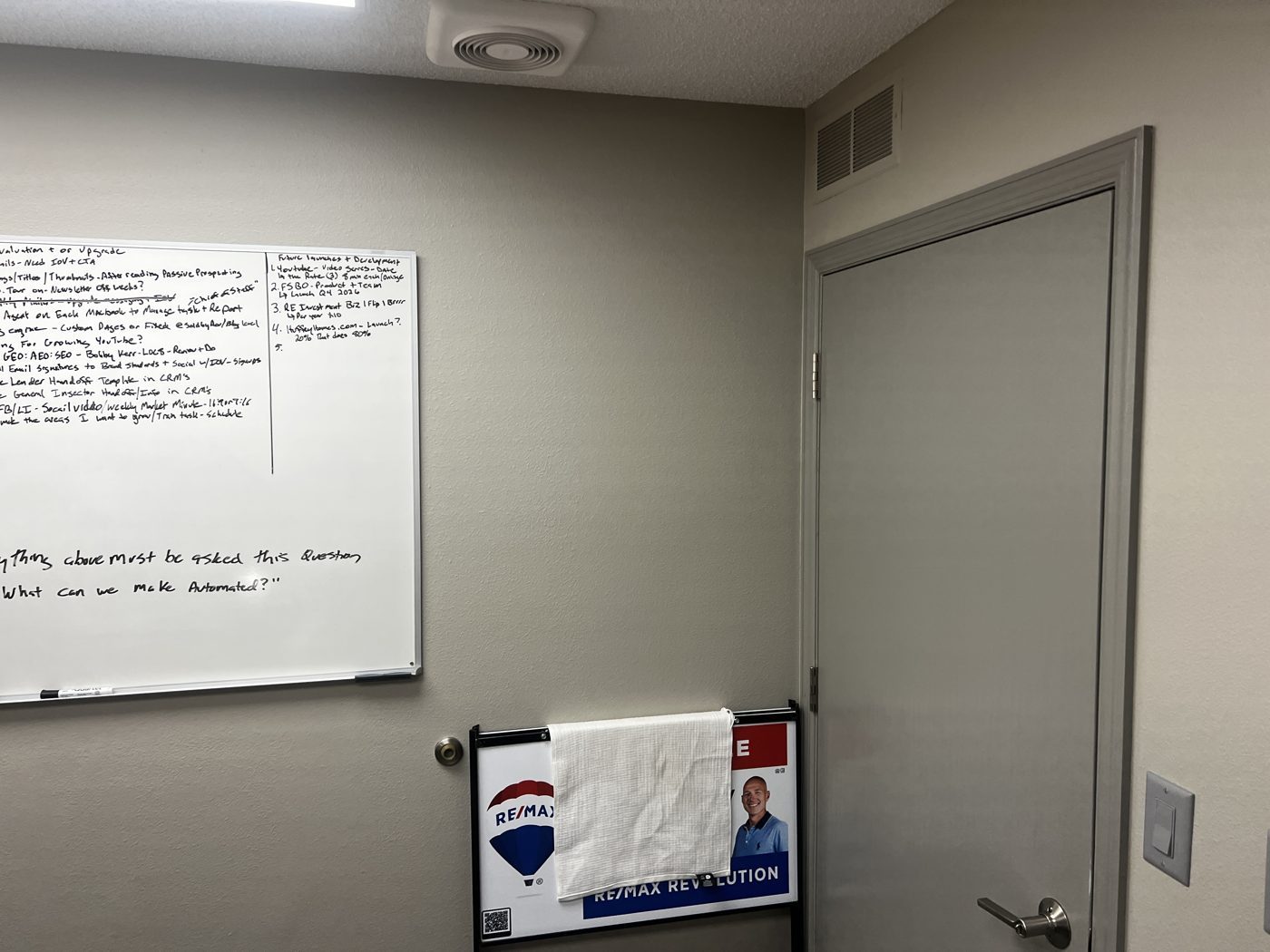 A meeting room with a whiteboard at the RE/MAX Revolution office.