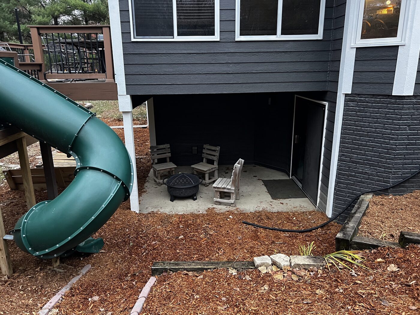A backyard with a deck, patio and a green tube slide at a Des Moines-area home.